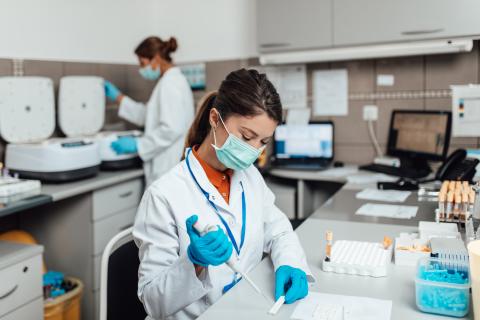 Two medical researchers wear masks while working in a lab